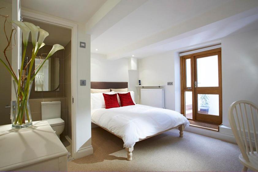 Dormitorio blanco con cama con almohadas rojas en Just a B, en Winchester
