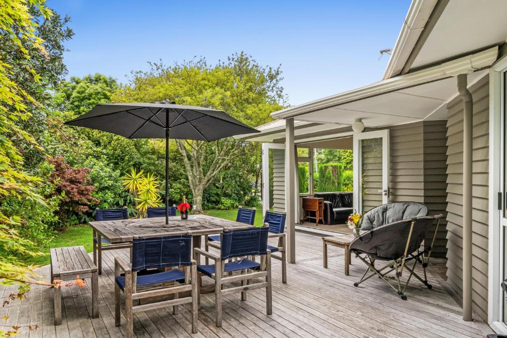 a patio with a table and chairs and an umbrella at Kohekohe Garden Cottage - Waikanae Holiday Home in Waikanae