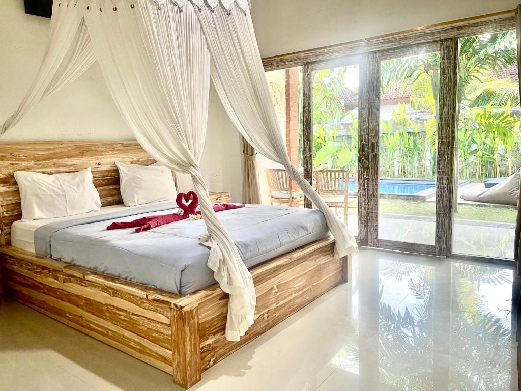 a bedroom with a bed with a red ribbon on it at Arjuna Uluwatu Guest House in Uluwatu