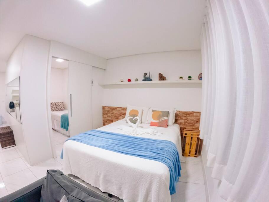 a white bedroom with a large bed with blue sheets at Flat na natureza in Bonito