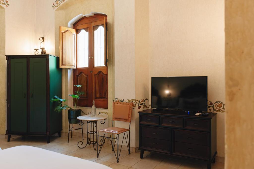 1 dormitorio con TV y mesa con sillas en Los Pilares Hotel, en Oaxaca City