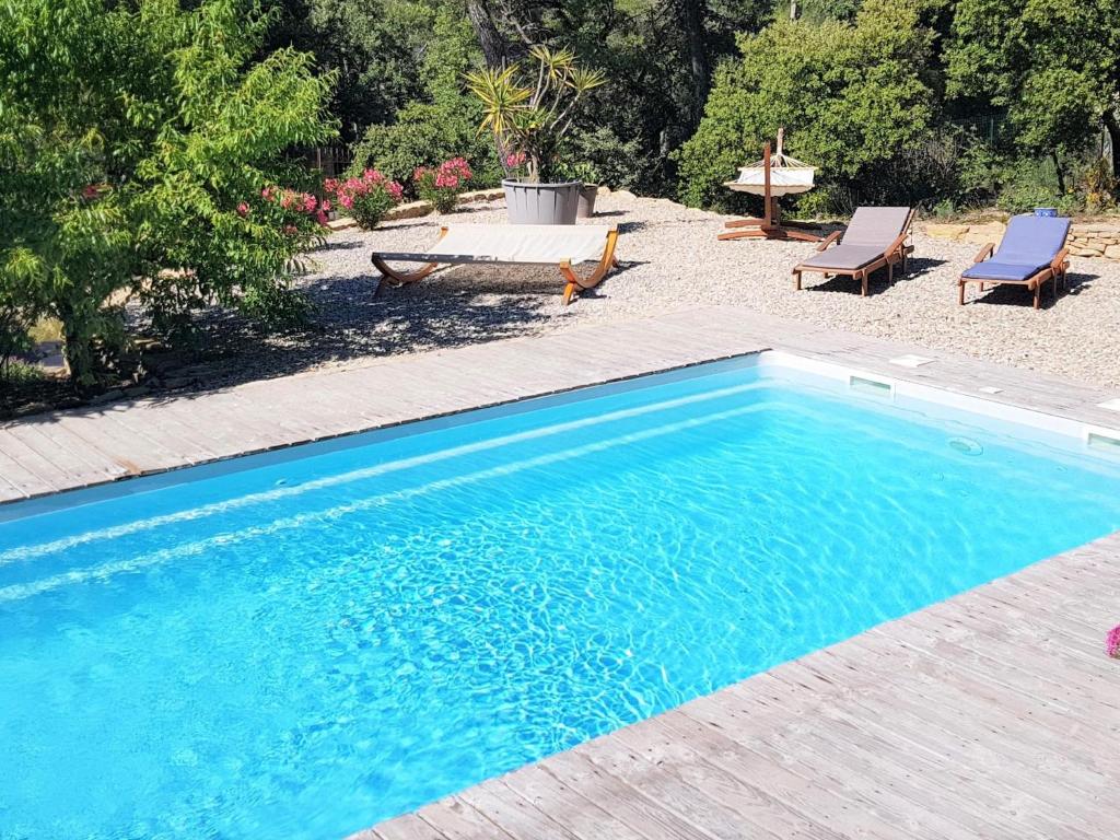 una piscina azul con 2 sillas y una mesa en La Pinede, en Faucon
