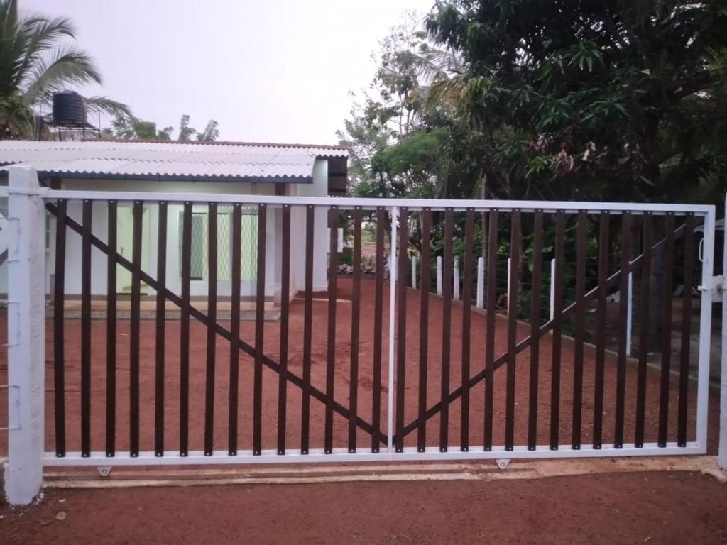 a white gate in front of a house at Cosy Holiday Home in Jayarajapuraya