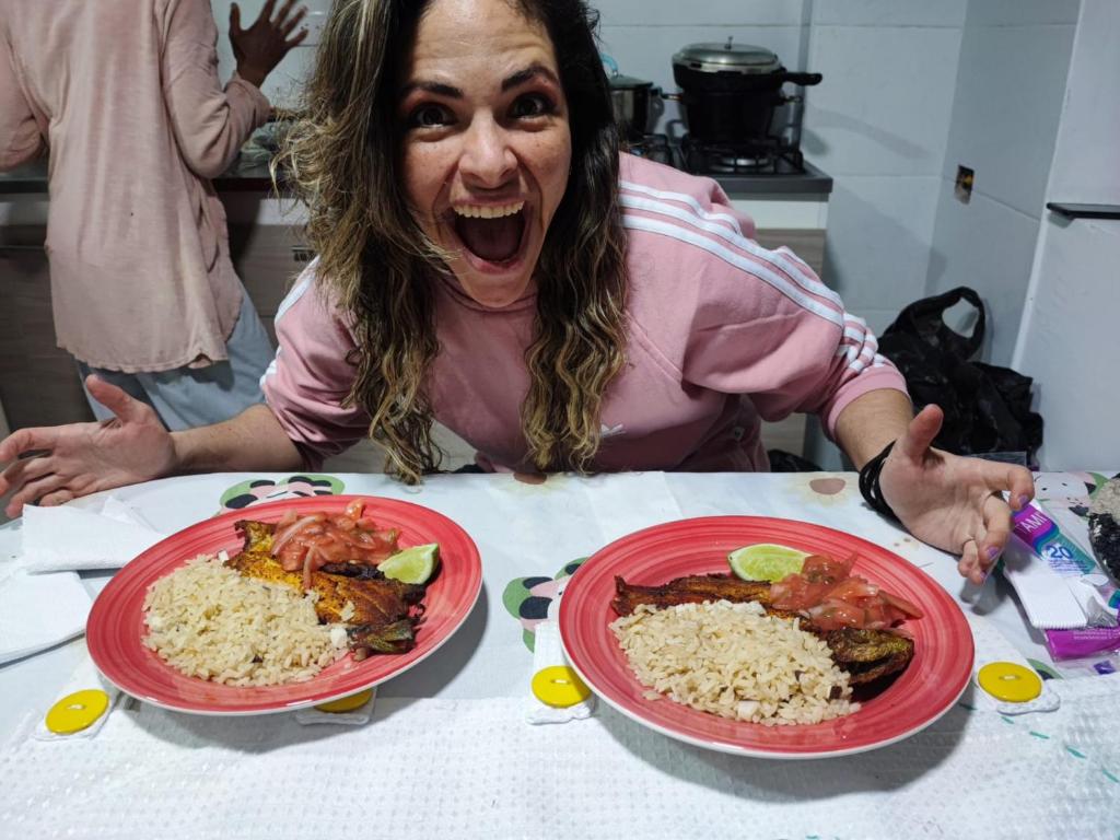 uma mulher sentada numa mesa com dois pratos de comida em Hostal Ninfa del Mar em Manizales