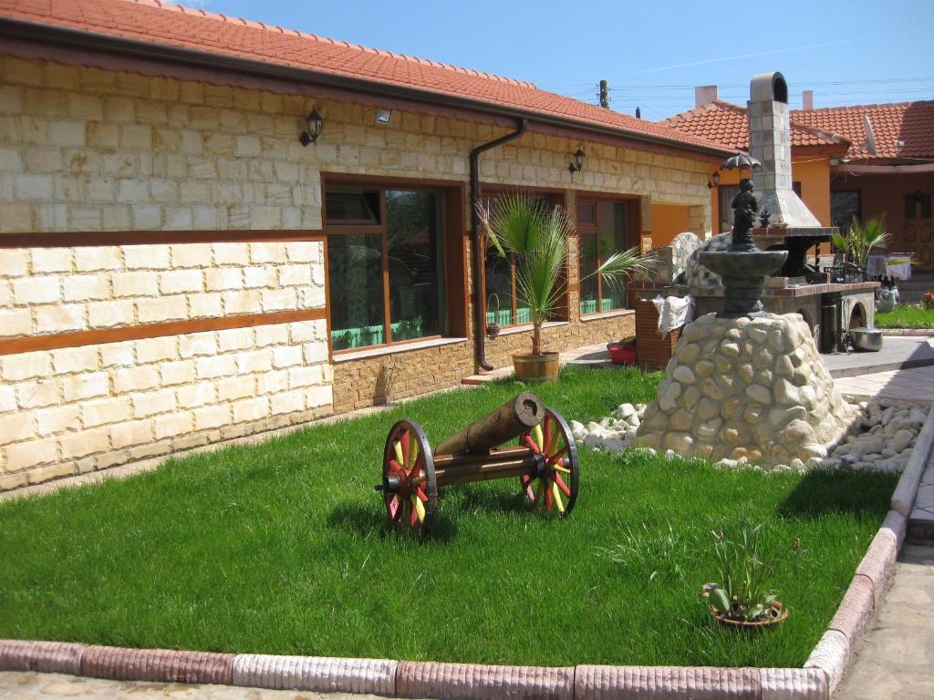 un giardino con un cannone nell'erba di fronte a una casa di Albena Guest House a Shabla