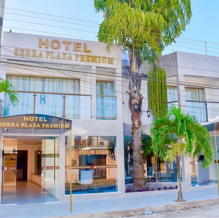 a hotel with palm trees in front of a building at Serra Plaza Premium in Serrinha