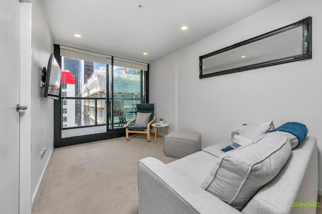 a living room with a couch and a window at QV Comfortable Downtown Apartment - 1136 in Auckland