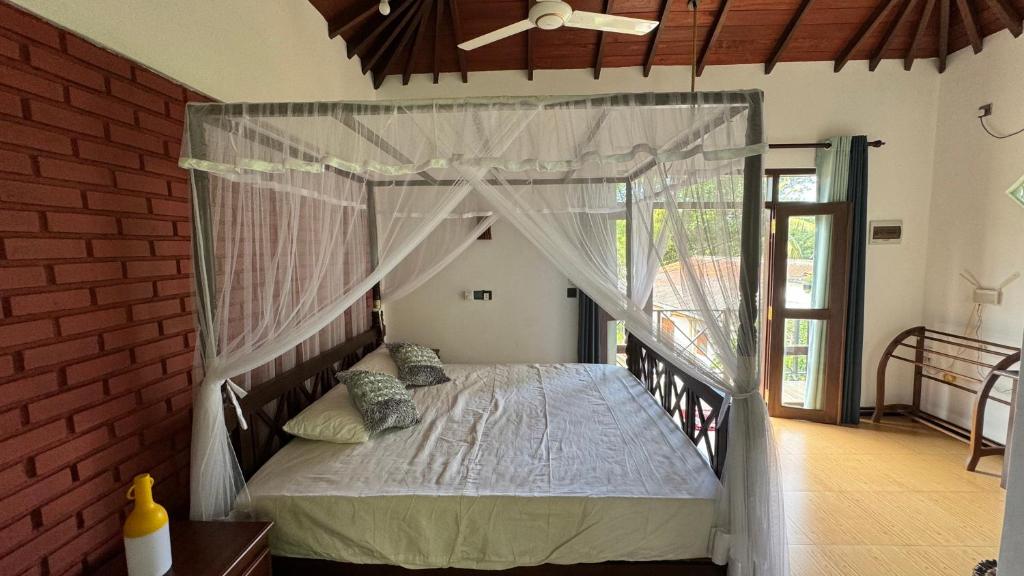 1 dormitorio con 1 cama con dosel en Dosemo Cabana, en Induruwa