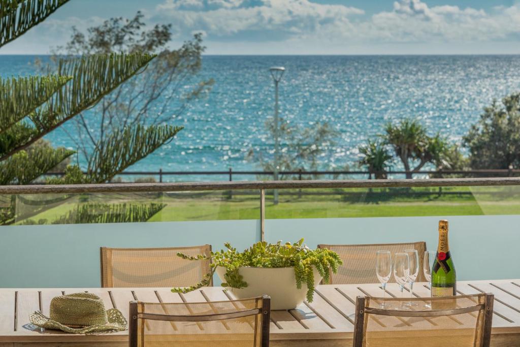 una mesa con una botella de vino y vistas al océano en Beach Suites en Byron Bay