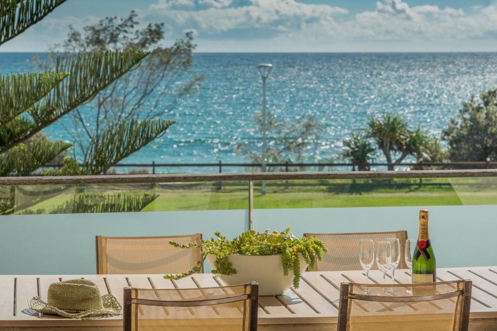uma mesa com uma garrafa de vinho e vista para o oceano em Beach Suites em Byron Bay