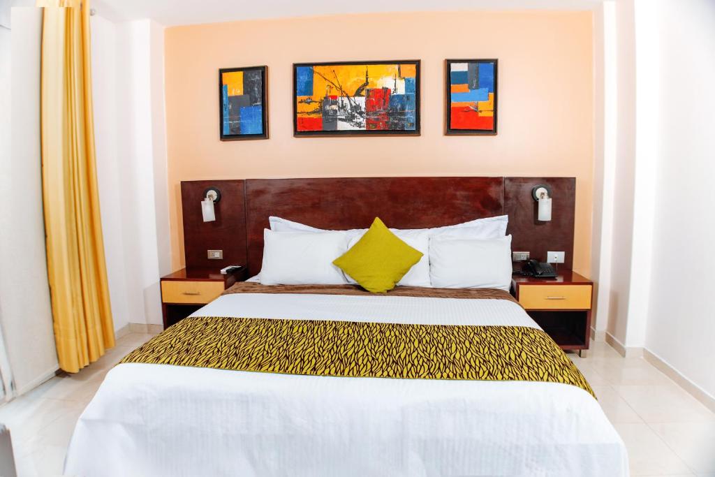 a hotel room with a large bed with yellow pillows at Hotel Luxor Cúcuta in Cúcuta