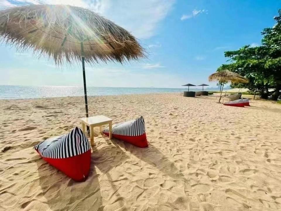 a beach with an umbrella and chairs on the sand at Grand Florida Beach condo in Na Jomtien