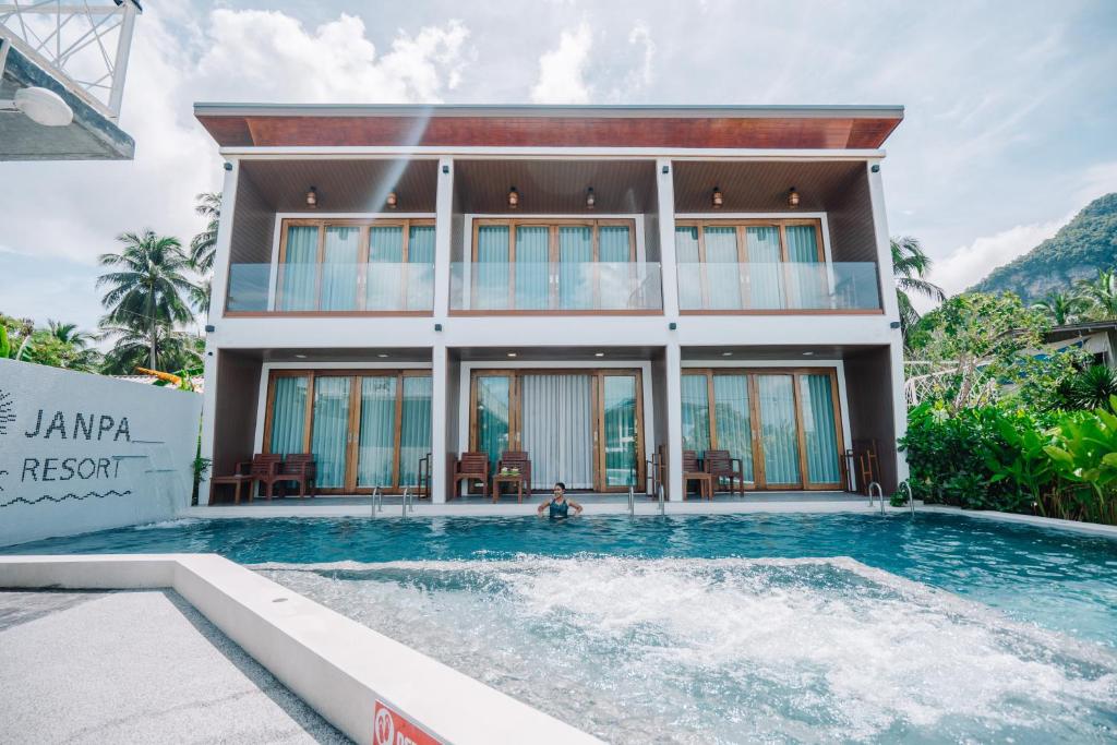 a villa with a swimming pool in front of a house at Janpa Resort in Don Sak