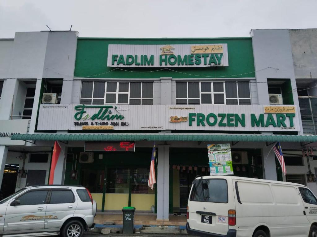 two white vans parked in front of a foreign market at Fadlim Homestay in Padang Serai