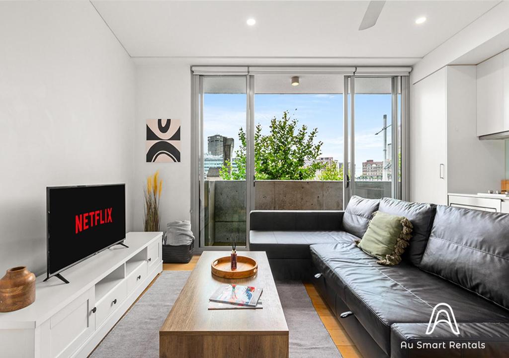 uma sala de estar com um sofá e uma televisão em Central stylish 1 bedroom with balcony and air-con em Sydney