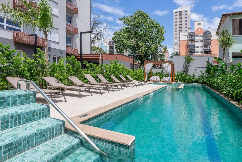 a swimming pool with lounge chairs next to a building at Likehome Connect in Porto Alegre