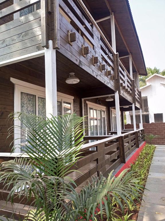 a house with a wooden facade with plants in front at Satva Cottages in Anjuna