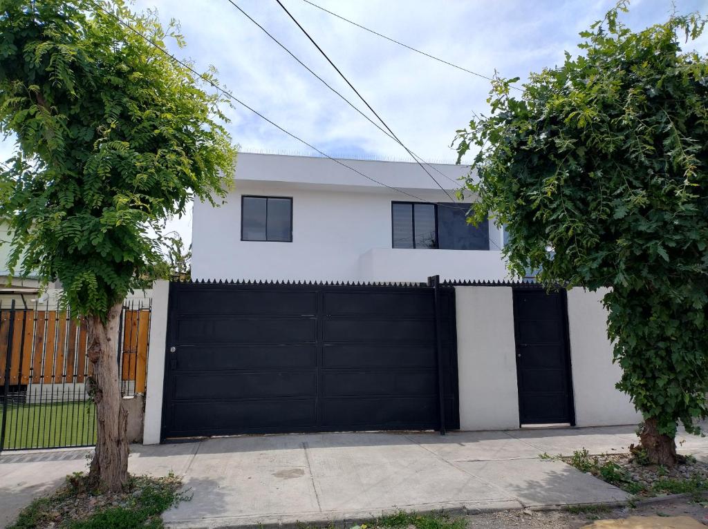 een wit huis met een zwarte garagedeur bij casa entera con estacionamiento in Santiago