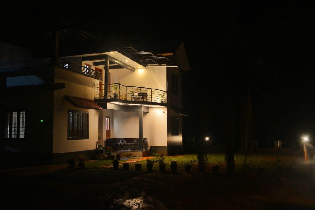 une maison éclairée la nuit dans l'établissement Coffee Roots, à Kalpatta