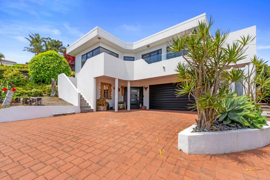 a large white house with a brick driveway at Bellevue Paradise - Tauranga Holiday Home in Tauranga