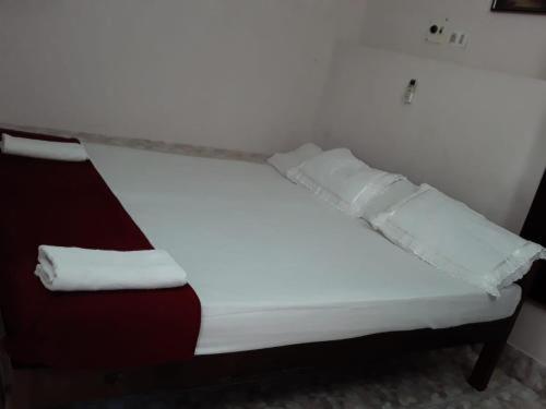 una cama blanca con sábanas y almohadas rojas y blancas en Luxury pool villa kovalam, en Trivandrum