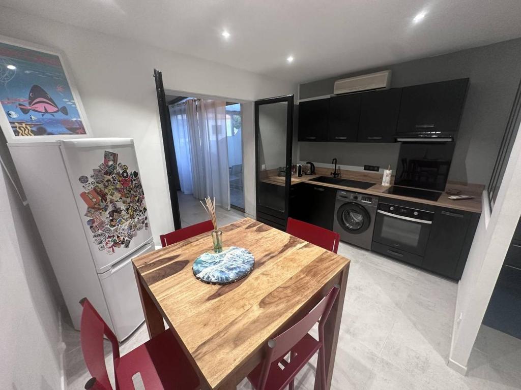 une cuisine avec une table en bois et des chaises rouges dans l'établissement Appartement T2 rénové avec clim, proche mer, 2 km du centre, WiFi fibre, tennis et animaux acceptés - FR-1-768-49, aux Issambres