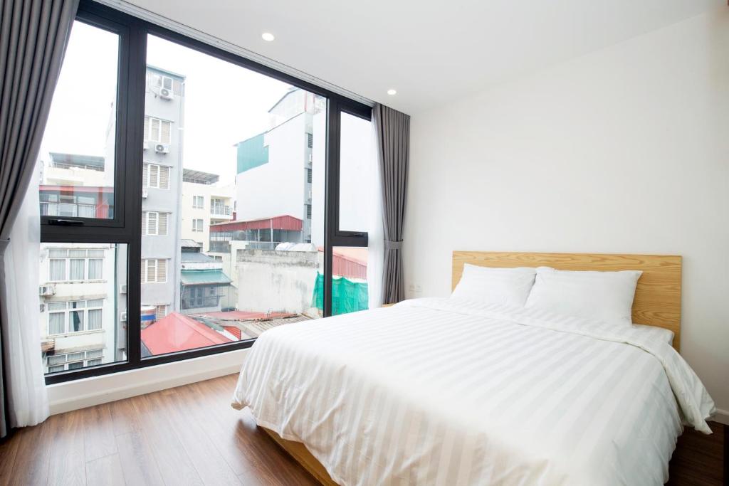 ハノイにあるSumitomo 14 Apartment - 50 Phan Ke Binh streetの大きな窓付きの客室の白いベッド1台