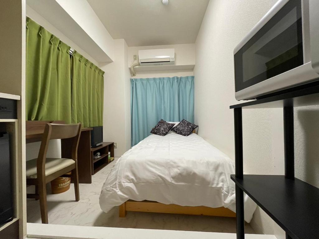 - une petite chambre avec un lit et une télévision dans l'établissement A&C STAY Shin-Osaka 41, à Osaka