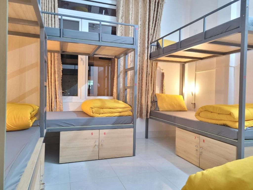 Habitación con 2 literas y almohadas amarillas. en Tiny Tigers Hostel, en Da Lat