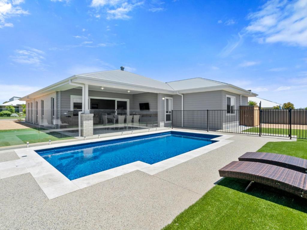 a home with a swimming pool in front of a house at Sunsets by the Lake in Yarrawonga