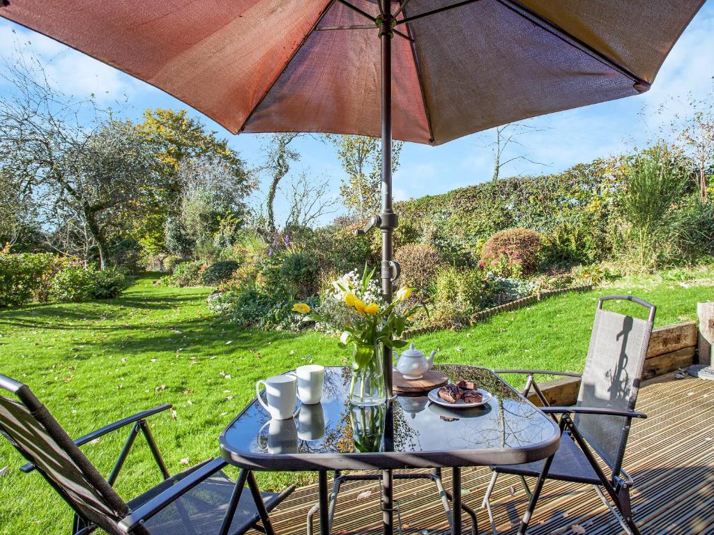 a table and chairs with an umbrella on a deck at Flaxpool Well Garden Room in Crowcombe