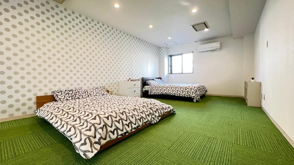1 dormitorio con 2 camas y alfombra verde en 心斎橋USJ155m2 Party OK JR駅徒歩1分 en Osaka