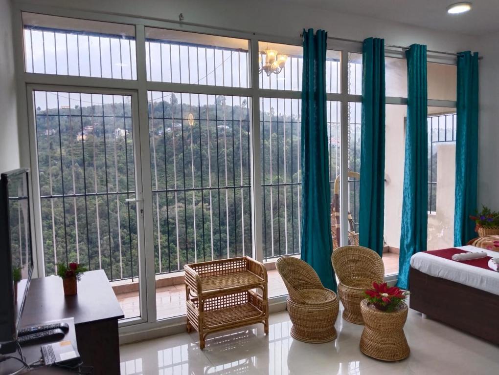 um quarto com uma grande janela com cortinas azuis em 4REST INN PRIVATE LIMITED em Kodaikanal
