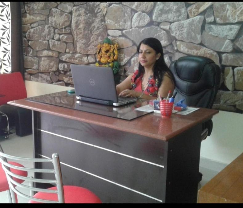 New Chandigarh Holiday Home في شانديغار: امرأة تجلس على طاولة مع جهاز كمبيوتر محمول