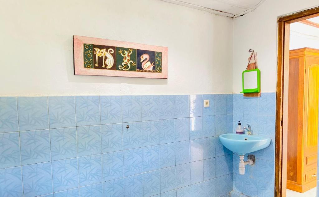 a bathroom with a sink and a blue tiled wall at suris bungalow 2 in Pabean Buleleng