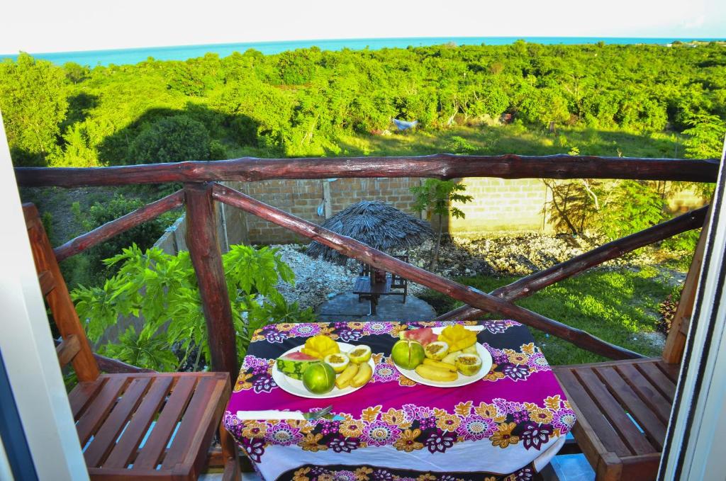 a table with a plate of fruit on a balcony at Nyota Apartment in Nungwi