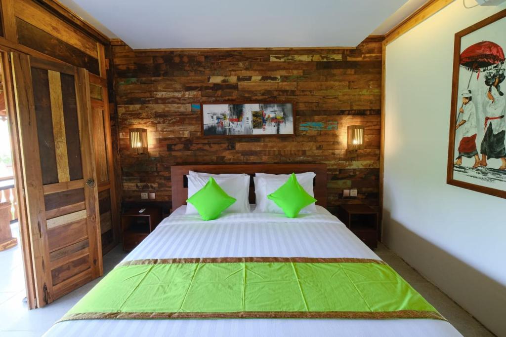 a bedroom with a bed with green pillows at Green Bali Guest House in Munggu