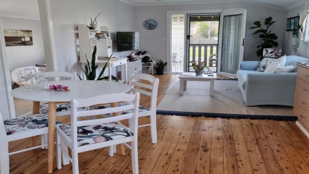 een keuken en een woonkamer met een witte tafel en stoelen bij Nonna's Retreat in Sussex inlet