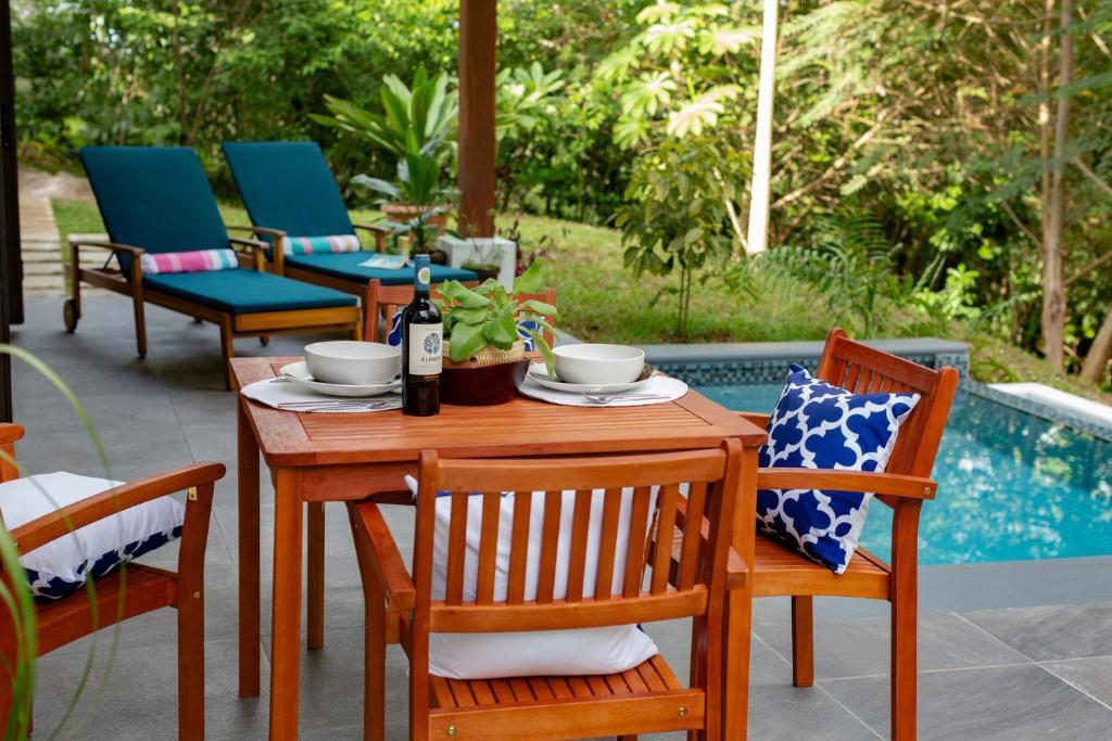 una mesa de madera con sillas y una botella de vino en Private Modern Villa Near Resort District en Benque Viejo del Carmen