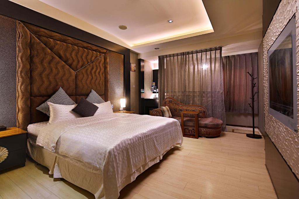 薇風情汽車旅館 - 台南館 في Liujia: غرفة نوم بسرير كبير وكرسي