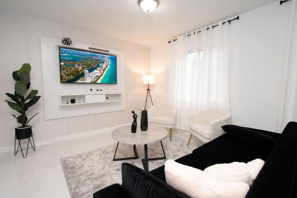 ein Wohnzimmer mit einem Sofa und einem TV an der Wand in der Unterkunft STAR HOME-wynwood/airport/miami in Miami