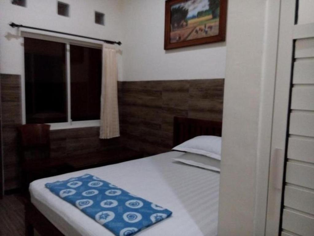 a small bedroom with a bed and a window at Rumah Tourist in Banyuwangi