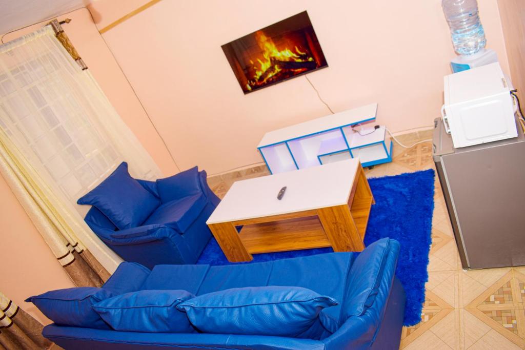 een woonkamer met twee blauwe banken en een tv bij Furnished one bedroom bnb in thika town, jomoko in Thika