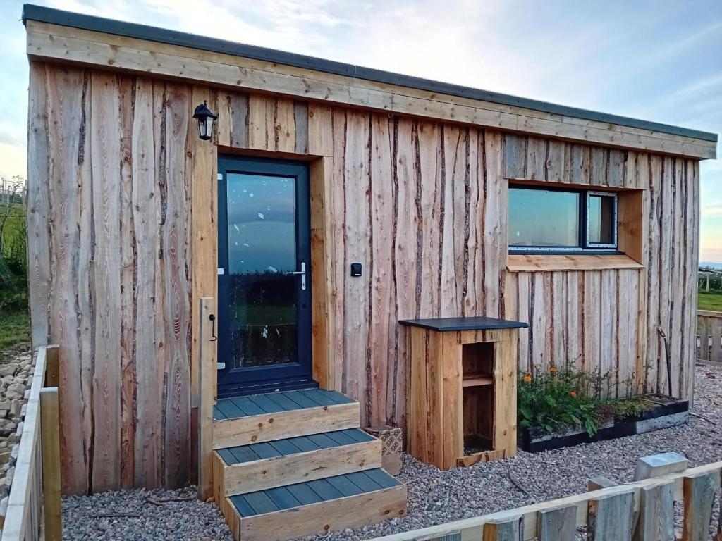 a wooden tiny house with a door and stairs at Honeysuckle Straw Bale Cabin in Dallas