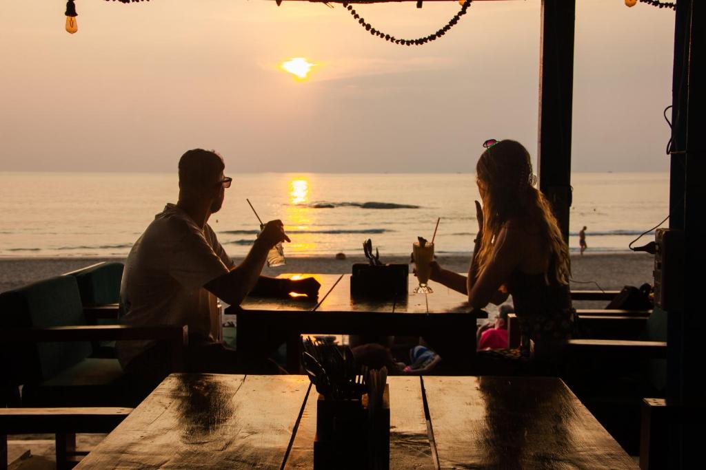 a man and woman sitting at a table at the beach at New Common Home in Agonda