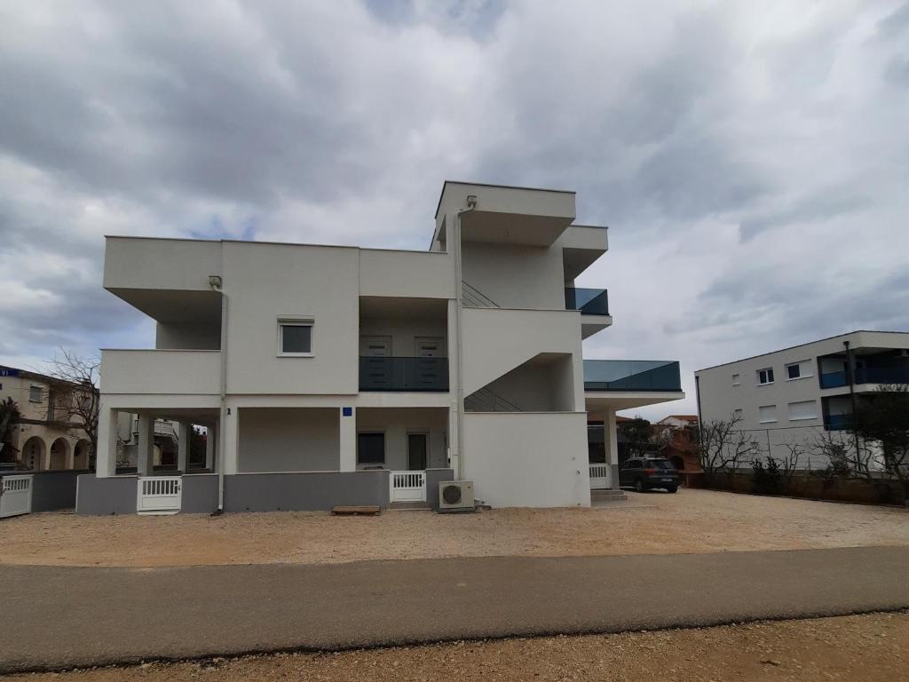 a white building in front of a parking lot at Apartments Matkovic in Vir