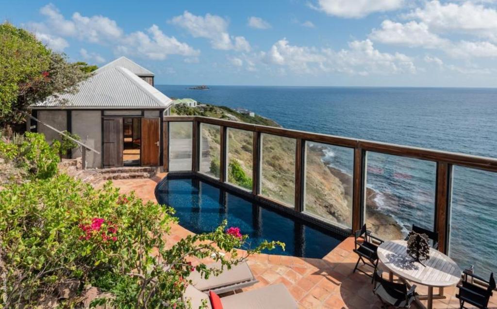 a house with a balcony with a view of the ocean at Saint Barth Villa 8 in Pointe Milou