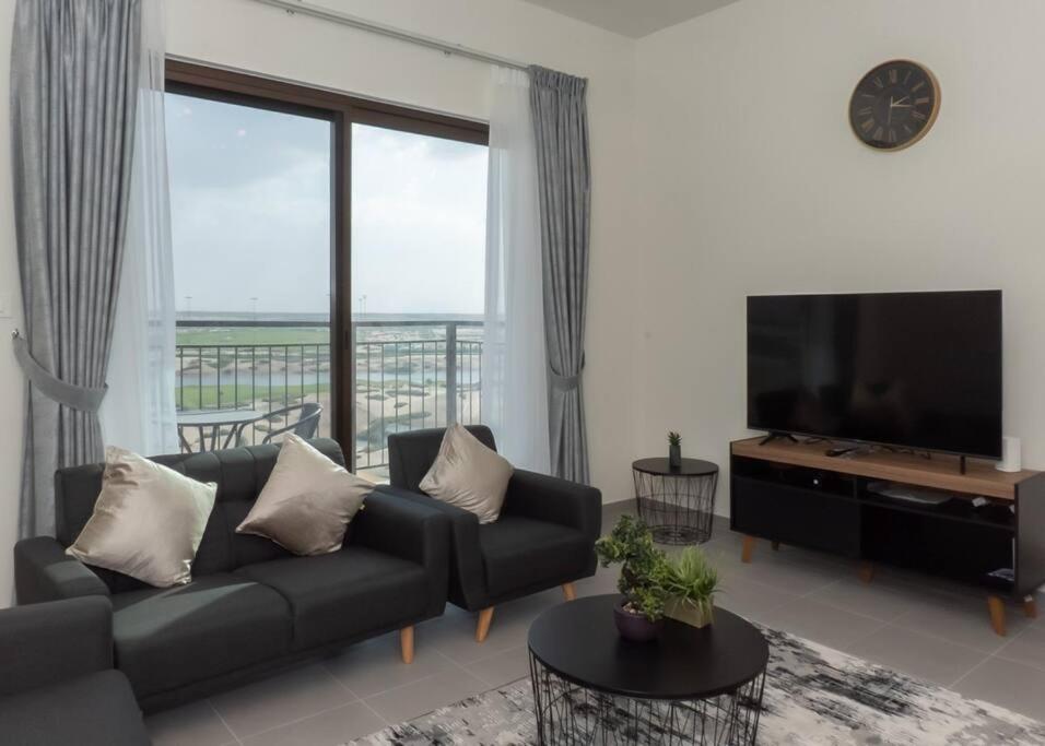 uma sala de estar com um sofá e uma televisão de ecrã plano em StoneTree - Furnished 1BR in Peaceful Community em Dubai