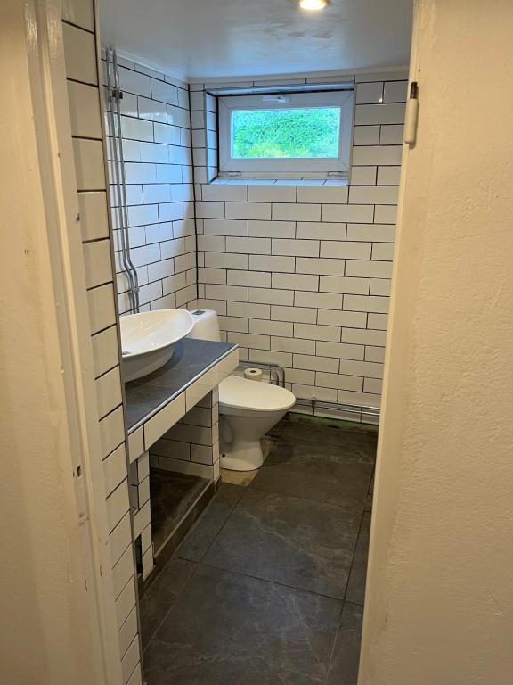 uma casa de banho com um WC, um lavatório e uma janela em Hedén Apartment em Kållered