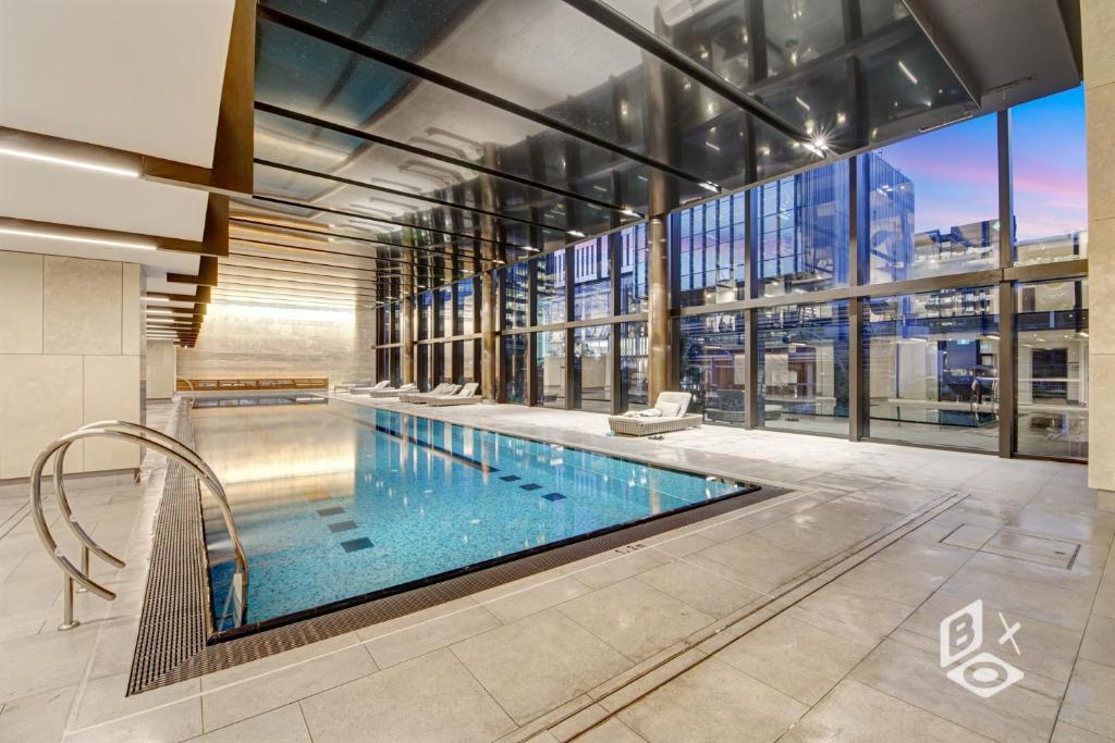 a large swimming pool in a building with a large window at Rest SkyHigh Melbourne Qtr Collection in Melbourne